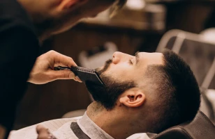Barbeiro alinhando a barba de cliente na The Barbers Aju, Aracaju