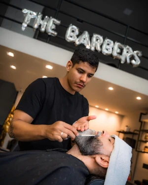 Barbeiro fazendo barba com navalha em cliente na The Barbers Aju, Aracaju