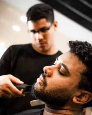 Barbeiro aparando a barba de cliente na The Barbers Aju, Aracaju